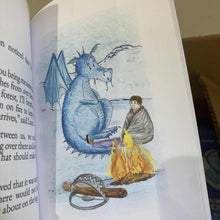 Load image into Gallery viewer, Blue dragon sitting next to man in a blanket, near a fire and a trap with a piece of wood in it