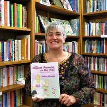 Load image into Gallery viewer, Smiling lady holding her book inside a book shop