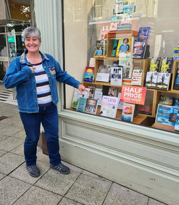 Smiling lady pointing at her book in Waterstone's window